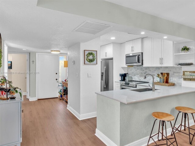1489 Fairway Rd, Pembroke Pines, FL 33026 - kitchen with appliances with stainless steel finishes, open shelves, a peninsula, light countertops, and a kitchen bar