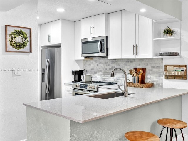 1489 Fairway Rd, Pembroke Pines, FL 33026 - kitchen with stainless steel appliances, a sink, open shelves, tasteful backsplash, and a peninsula