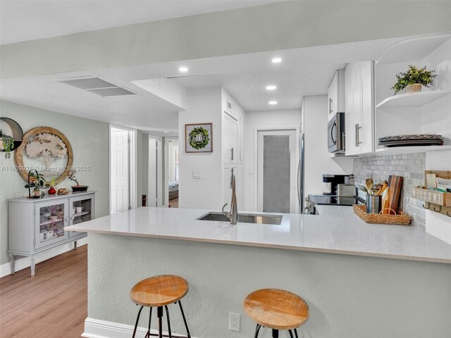 1489 Fairway Rd, Pembroke Pines, FL 33026 - kitchen with open shelves, a peninsula, a sink, white cabinetry, and stainless steel appliances