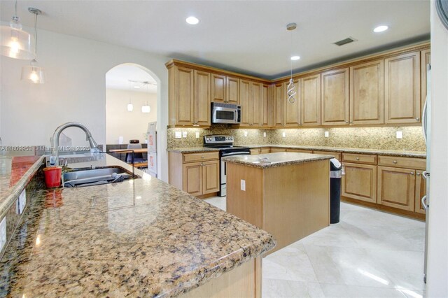 7753 SW 193rd St, Cutler Bay, FL 33157 - kitchen with appliances with stainless steel finishes, a kitchen island, a sink, arched walkways, and decorative backsplash