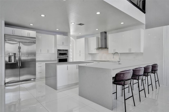 10457 Laurel Rd, Davie, FL 33328 - kitchen featuring wall chimney exhaust hood, stainless steel appliances, recessed lighting, a breakfast bar area, and a peninsula