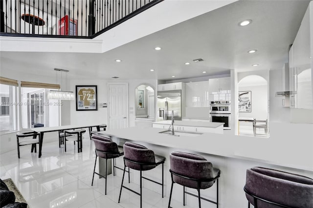 10457 Laurel Rd, Davie, FL 33328 - kitchen featuring modern cabinets, arched walkways, appliances with stainless steel finishes, a sink, and white cabinets