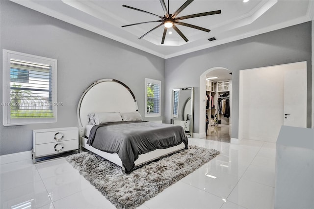 10457 Laurel Rd, Davie, FL 33328 - bedroom featuring a tray ceiling, arched walkways, crown molding, tile patterned floors, and a walk in closet