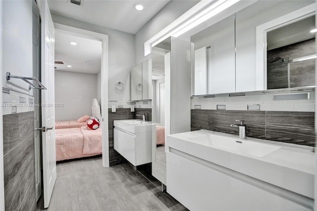 10457 Laurel Rd, Davie, FL 33328 - ensuite bathroom featuring decorative backsplash, two vanities, recessed lighting, and wood finished floors