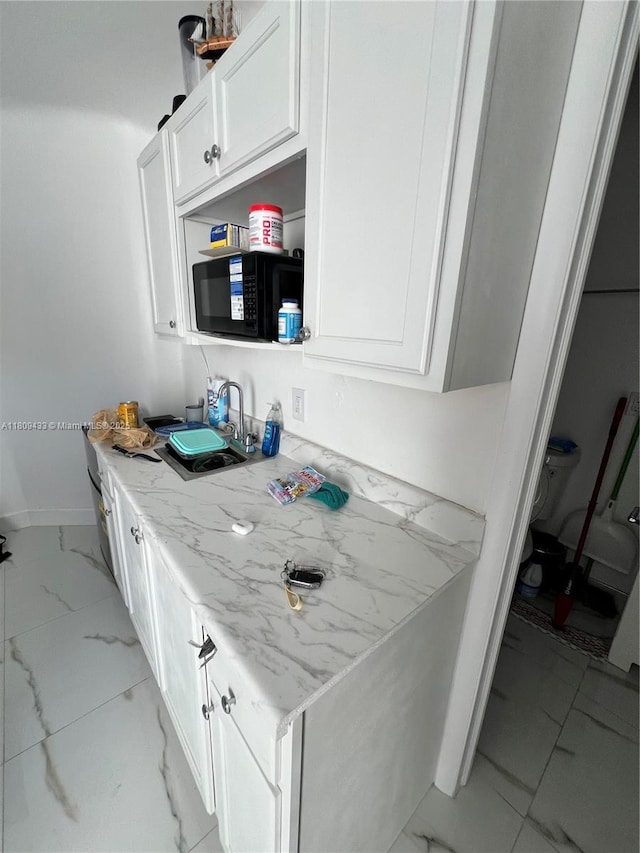 7821 NW 30th St, Davie, FL 33024 - kitchen with black microwave, light marble finish floors, and white cabinets