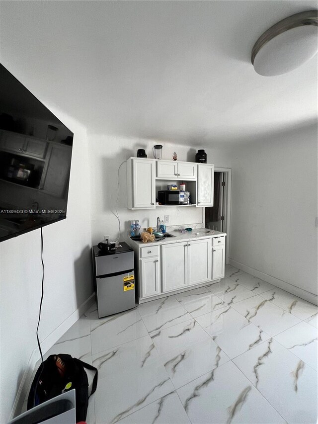 7821 NW 30th St, Davie, FL 33024 - kitchen with light marble finish floors, black microwave, baseboards, and white cabinets