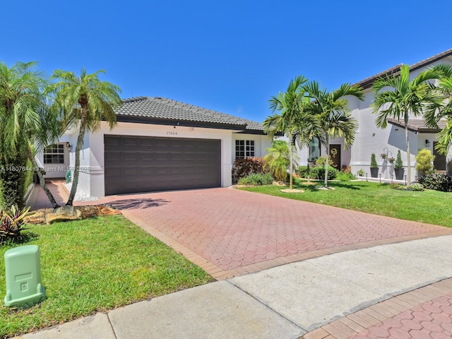 17654 SW 5th Ct, Pembroke Pines, FL 33029 - mediterranean / spanish-style home featuring stucco siding, decorative driveway, an attached garage, a tiled roof, and a front lawn