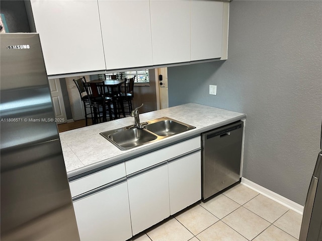 301 SW 86th Ave Unit 208, Pembroke Pines, FL 33025 - kitchen with stainless steel dishwasher, freestanding refrigerator, a sink, white cabinets, and a textured wall