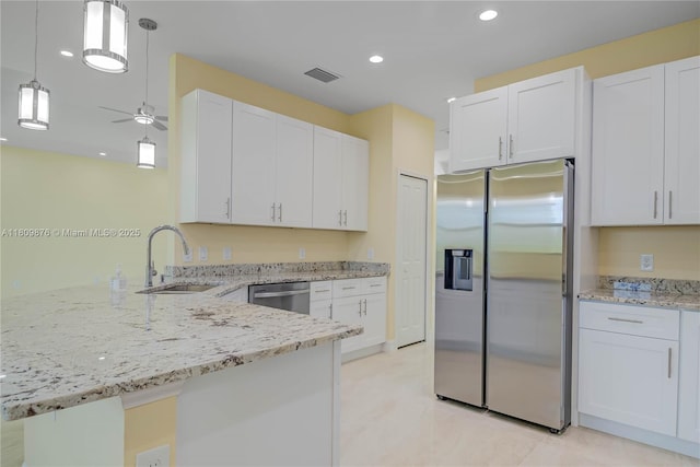 637 Cardinal St E, Lehigh Acres, FL 33974 - kitchen featuring appliances with stainless steel finishes, a sink, a peninsula, white cabinetry, and light stone countertops