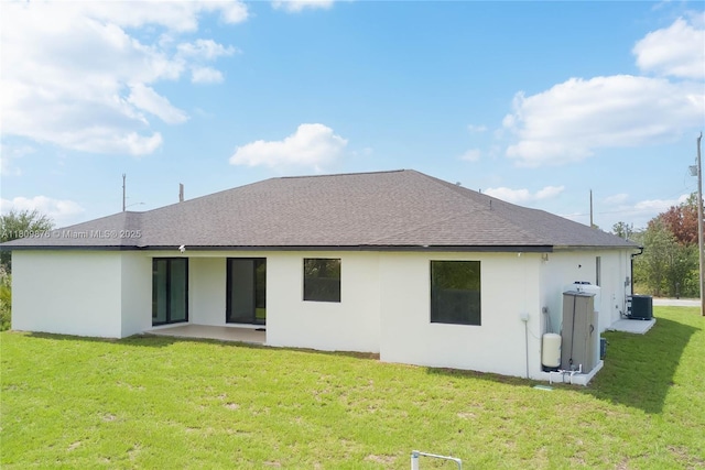 637 Cardinal St E, Lehigh Acres, FL 33974 - back of property with central AC unit, a shingled roof, stucco siding, a lawn, and a patio