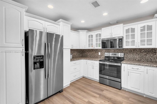 4271 SW 67th Ter, Davie, FL 33314 - kitchen featuring stainless steel appliances, glass insert cabinets, dark stone counters, white cabinets, and decorative backsplash