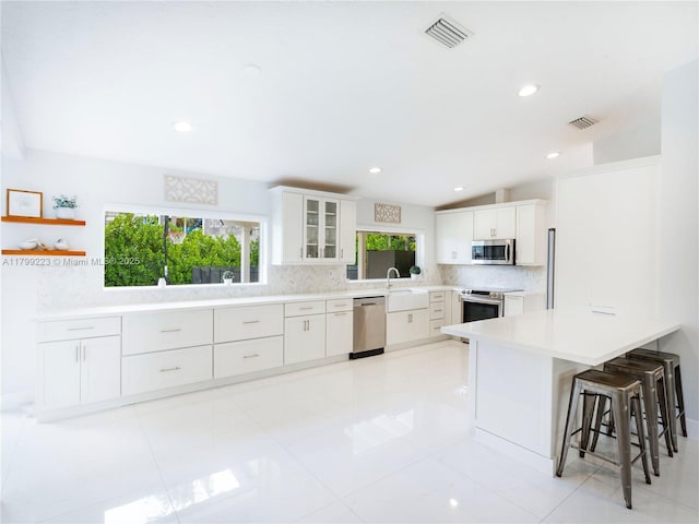 11145 SW 126th St, Miami, FL 33176 - kitchen featuring appliances with stainless steel finishes, decorative backsplash, a kitchen bar, a sink, and white cabinets
