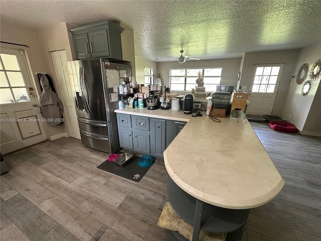 1230 F Rd, Loxahatchee, FL 33470 - kitchen featuring stainless steel fridge with ice dispenser, a peninsula, wood finished floors, a textured ceiling, and a ceiling fan