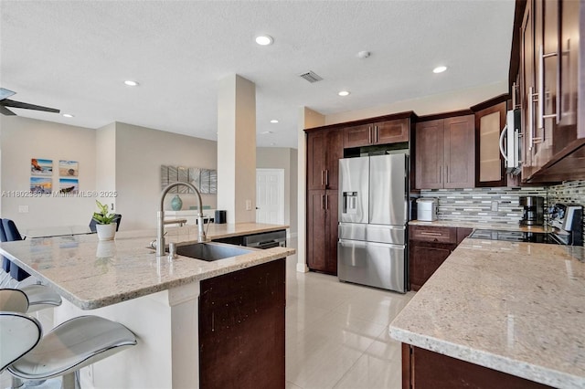 1070 Briar Ridge Rd, Weston, FL 33327 - kitchen with appliances with stainless steel finishes, a sink, light stone counters, a breakfast bar area, and decorative backsplash