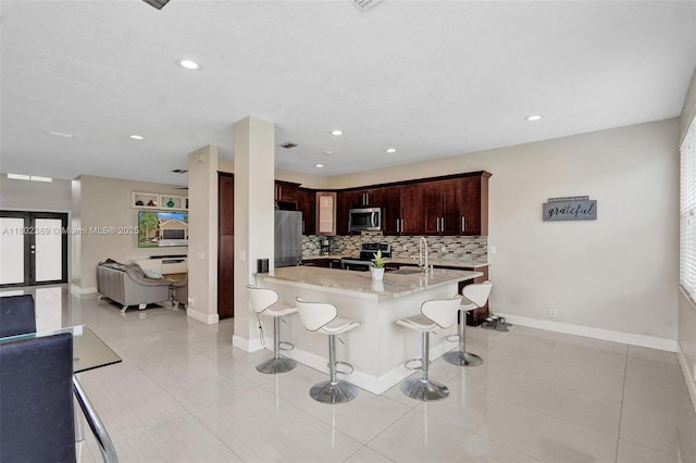 1070 Briar Ridge Rd, Weston, FL 33327 - kitchen with appliances with stainless steel finishes, a breakfast bar, decorative backsplash, light stone counters, and light tile patterned floors