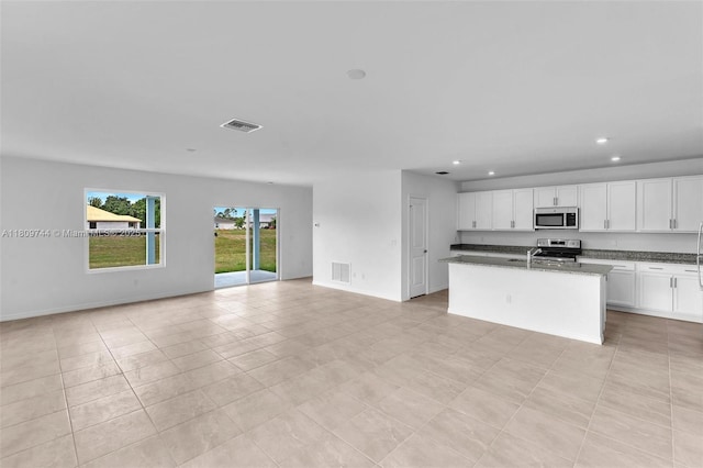 1130 SW Jericho Ave, Port St Lucie, FL 34953 - kitchen with stainless steel appliances, open floor plan, white cabinets, recessed lighting, and a center island with sink
