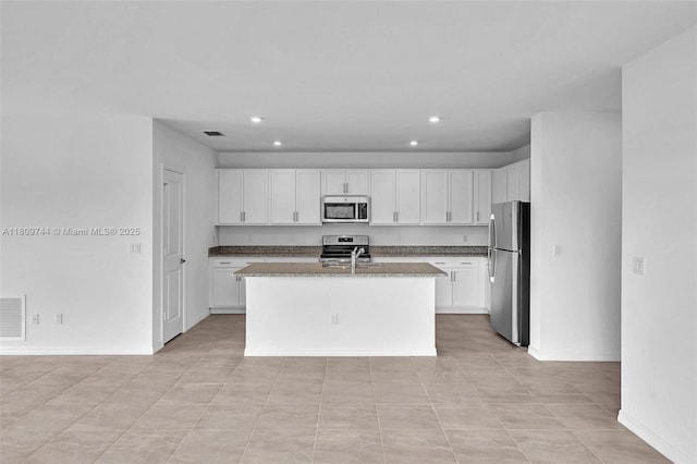 1130 SW Jericho Ave, Port St Lucie, FL 34953 - kitchen featuring stainless steel appliances, white cabinets, recessed lighting, an island with sink, and dark stone countertops