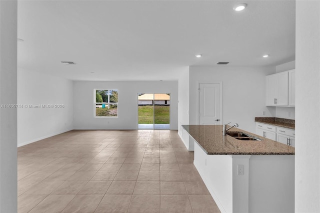 1130 SW Jericho Ave, Port St Lucie, FL 34953 - kitchen featuring recessed lighting, light tile patterned flooring, dark stone counters, white cabinetry, and open floor plan