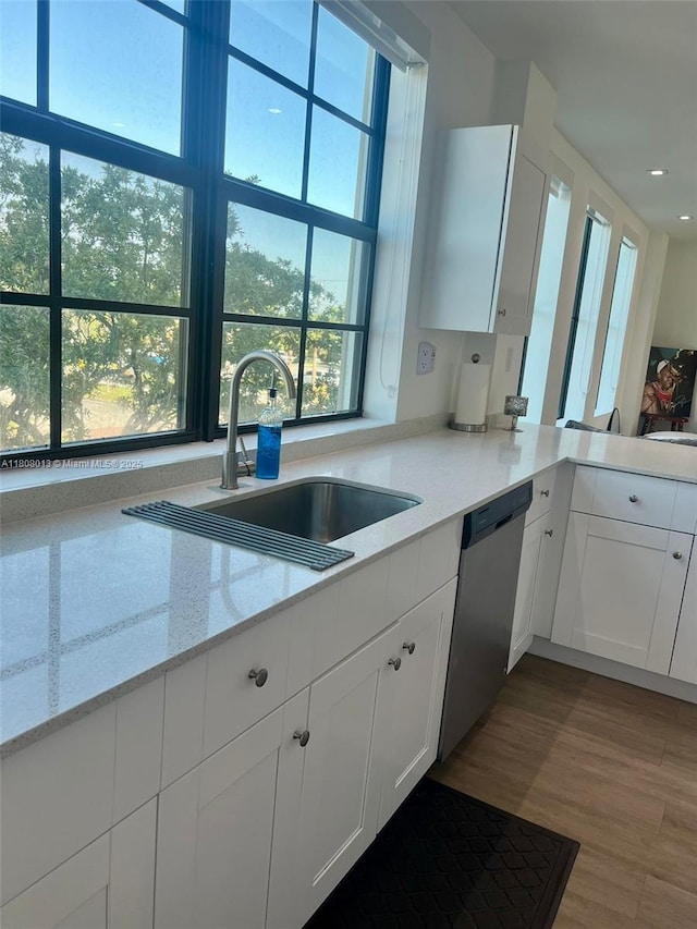 4100 SW 64th Ave Unit 201, Davie, FL 33314 - kitchen with a sink, stainless steel dishwasher, white cabinets, wood finished floors, and light stone counters