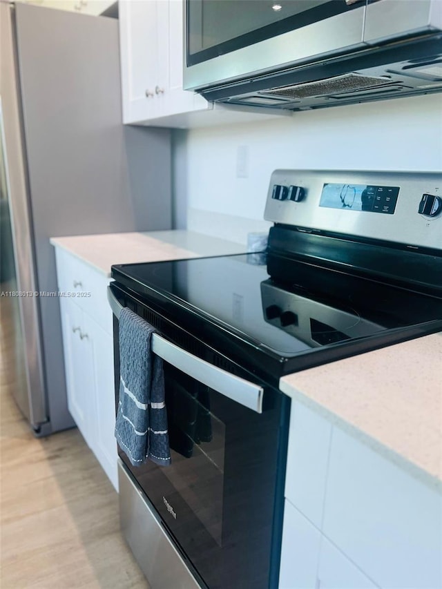 4100 SW 64th Ave Unit 201, Davie, FL 33314 - kitchen with stainless steel appliances, white cabinetry, light countertops, and light wood-style flooring