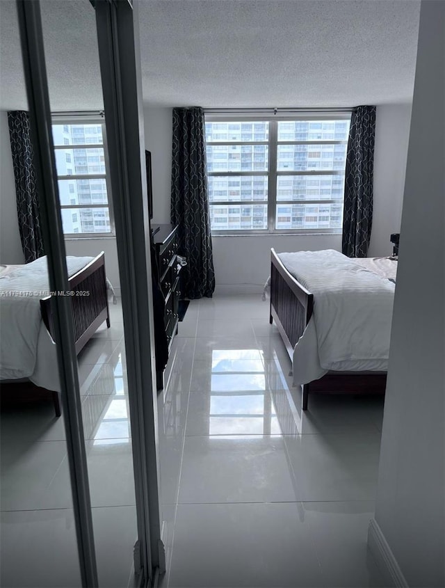 2780 NE 183rd St Unit 1110, Aventura, FL 33160 - bedroom with a textured ceiling, light tile patterned floors, and baseboards