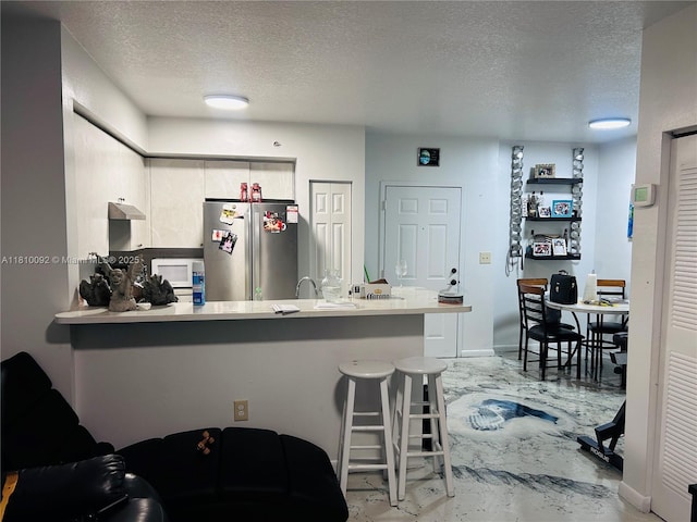 11040 SW 196th St Unit 209, Cutler Bay, FL 33157 - kitchen with freestanding refrigerator, a textured ceiling, a peninsula, light countertops, and under cabinet range hood
