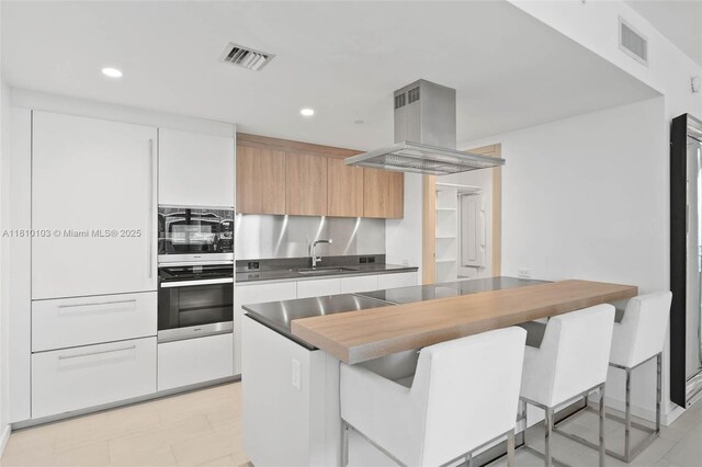 1000 Brickell Plz Unit 4209, Miami, FL 33131 - kitchen with oven, ventilation hood, a sink, modern cabinets, and a breakfast bar