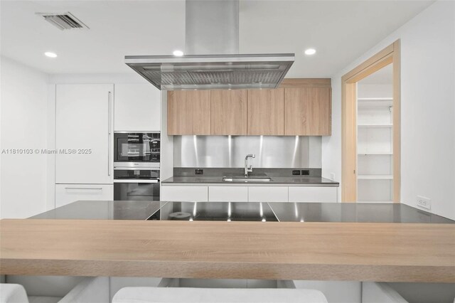 1000 Brickell Plz Unit 4209, Miami, FL 33131 - kitchen featuring oven, a sink, island range hood, modern cabinets, and dark countertops