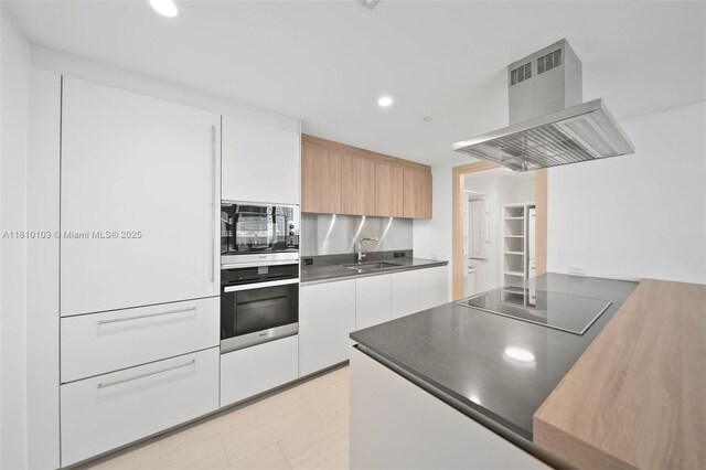 1000 Brickell Plz Unit 4209, Miami, FL 33131 - kitchen with range hood, stainless steel oven, black electric cooktop, modern cabinets, and built in microwave