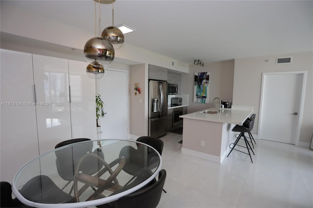325 S Biscayne Blvd Unit 1822, Miami, FL 33131 - kitchen with appliances with stainless steel finishes, a sink, a breakfast bar area, light countertops, and light tile patterned floors