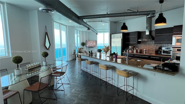 700 NE 25th St Unit 1703, Miami, FL 33137 - kitchen with dark cabinetry, a sink, a kitchen bar, and healthy amount of natural light