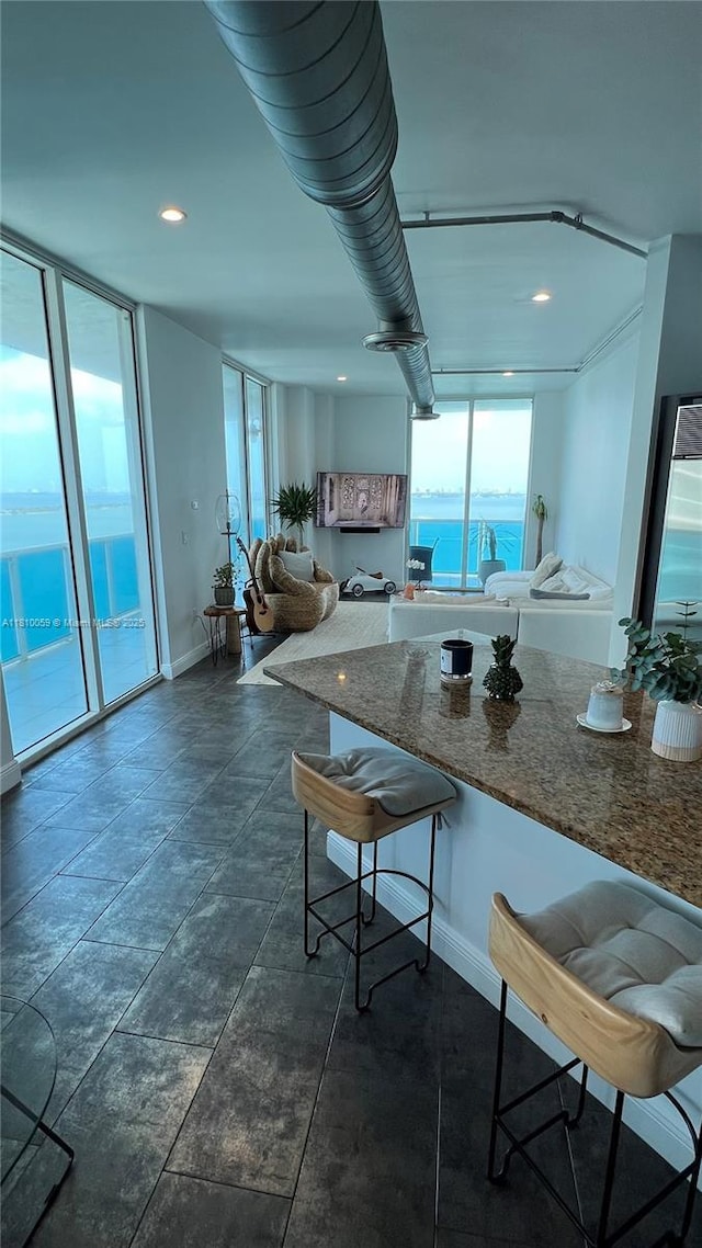 700 NE 25th St Unit 1703, Miami, FL 33137 - kitchen with a kitchen breakfast bar, baseboards, dark stone counters, a water view, and recessed lighting