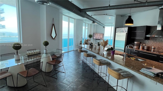 700 NE 25th St Unit 1703, Miami, FL 33137 - kitchen with a sink, dark stone countertops, hanging light fixtures, a kitchen bar, and black electric stovetop