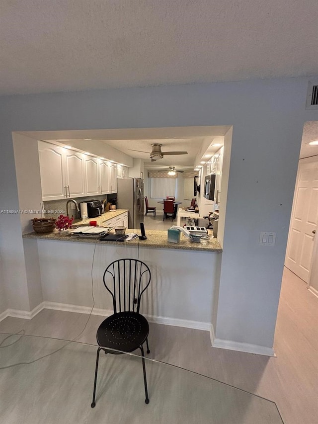 7443 Fairfax Dr Unit 208, Tamarac, FL 33321 - kitchen featuring stainless steel refrigerator with ice dispenser, white cabinets, a peninsula, baseboards, and a ceiling fan