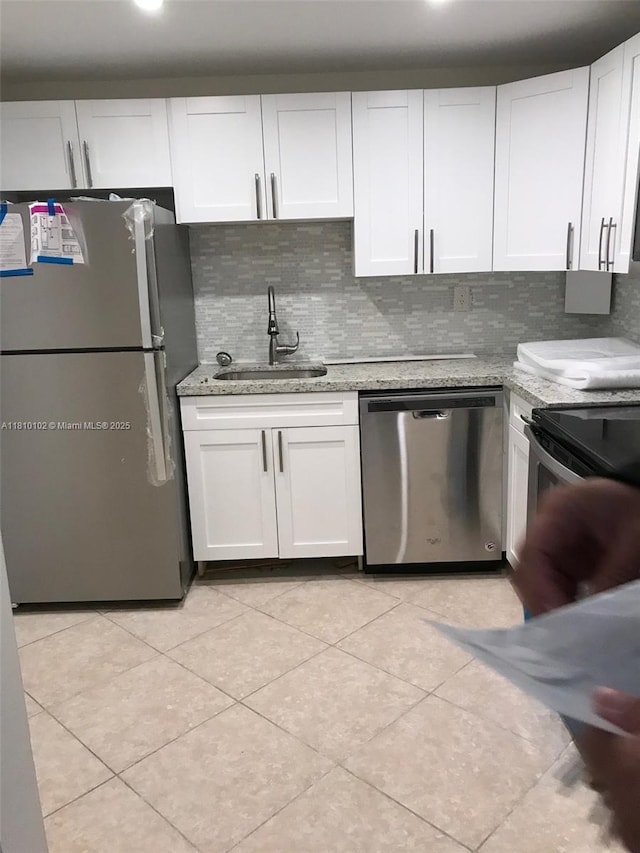 200 178th Dr Unit 505, Sunny Isles Beach, FL 33160 - kitchen featuring stainless steel appliances, a sink, white cabinetry, tasteful backsplash, and light stone counters
