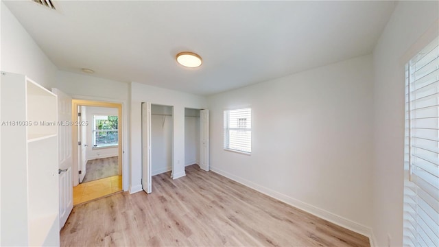 7 Montilla Ave, Coral Gables, FL 33134 - unfurnished bedroom with multiple windows, light wood-type flooring, baseboards, and two closets