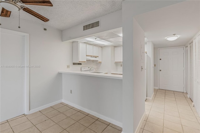 540 Brickell Key Dr Unit 718, Miami, FL 33131 - kitchen featuring under cabinet range hood, a ceiling fan, light tile patterned floors, white cabinets, and a textured ceiling