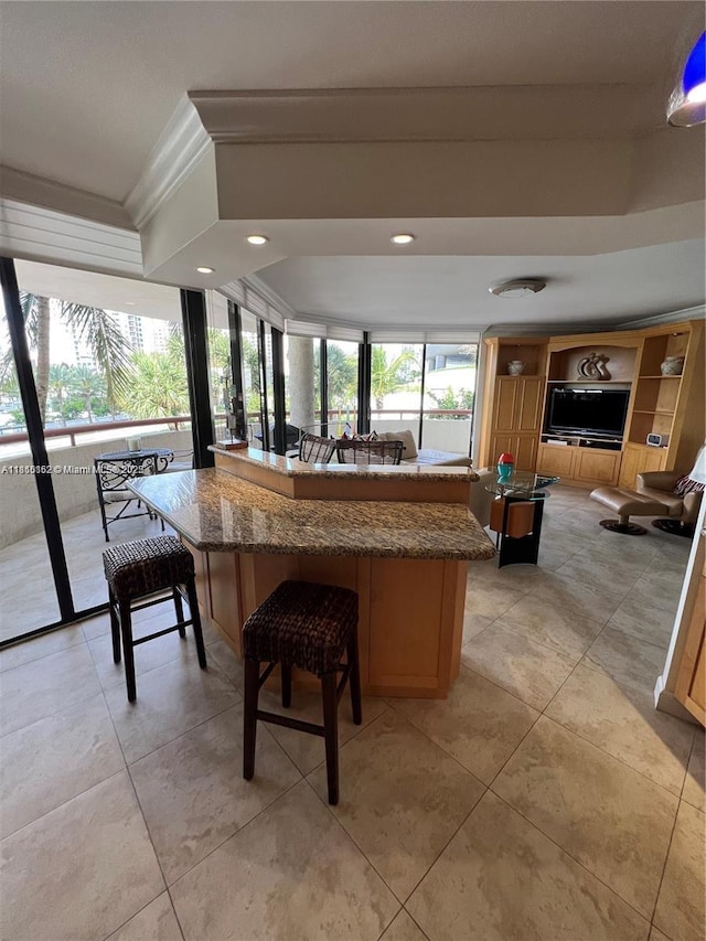 15645 Collins Ave Unit 301, Sunny Isles Beach, FL 33160 - kitchen featuring dark stone countertops, ornamental molding, a kitchen breakfast bar, recessed lighting, and light tile patterned flooring