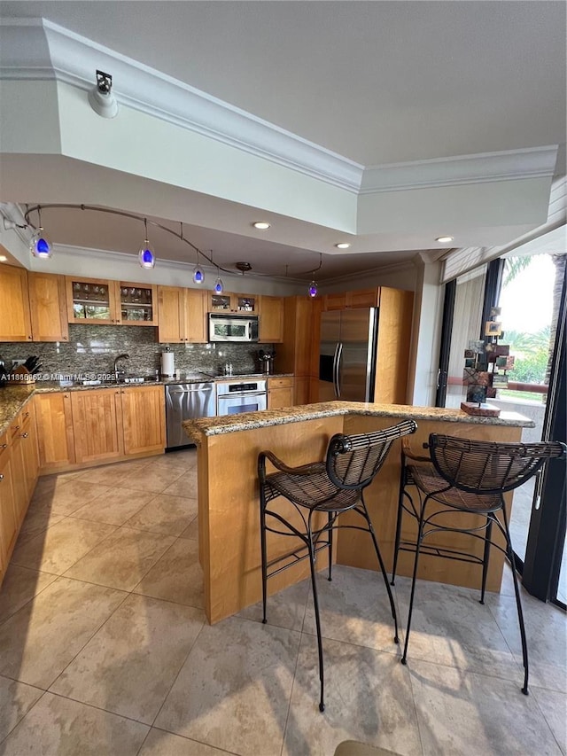 15645 Collins Ave Unit 301, Sunny Isles Beach, FL 33160 - kitchen featuring ornamental molding, stainless steel appliances, tasteful backsplash, a sink, and a kitchen bar