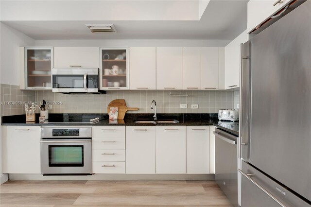 3470 E Coast Ave Unit H1402, Miami, FL 33137 - kitchen with stainless steel appliances, a sink, light wood-style floors, white cabinets, and decorative backsplash