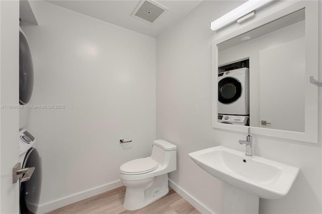 3470 E Coast Ave Unit H1402, Miami, FL 33137 - bathroom featuring stacked washer / dryer, wood finished floors, toilet, baseboards, and a sink