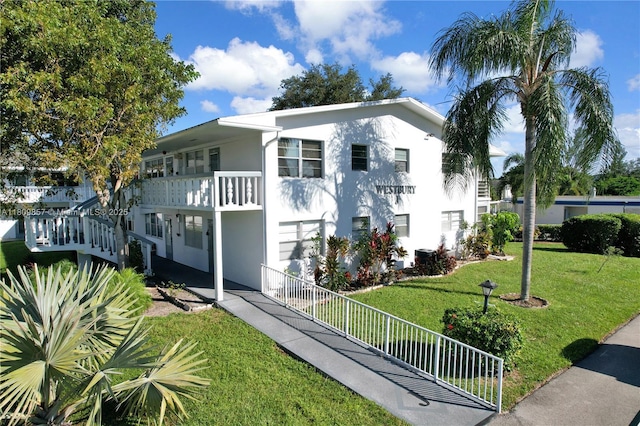 182 Westbury J 182, Deerfield Beach, FL 33442 - view of front of home featuring stucco siding, a front lawn, an attached garage, and a balcony