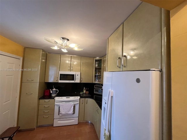 3551 NE 169th St Unit 301, North Miami Beach, FL 33160 - kitchen with white appliances, dark countertops, a chandelier, light tile patterned floors, and glass insert cabinets