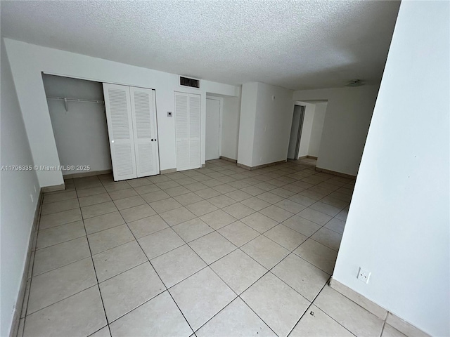 17021 N Bay Rd Unit 329, Sunny Isles Beach, FL 33160 - unfurnished bedroom featuring a textured ceiling, multiple closets, light tile patterned floors, and baseboards