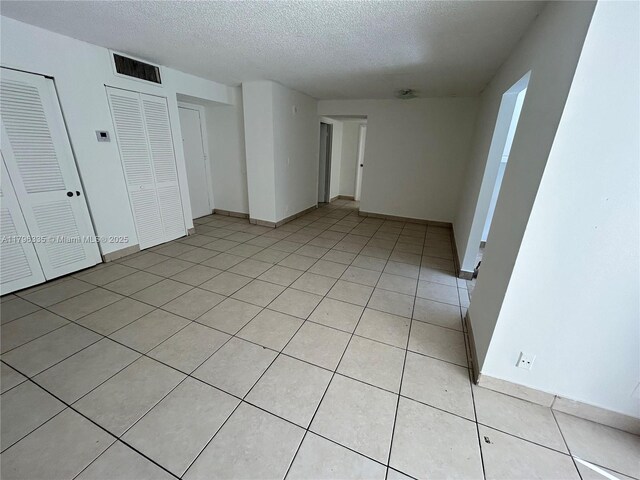 17021 N Bay Rd Unit 329, Sunny Isles Beach, FL 33160 - unfurnished bedroom with a textured ceiling, baseboards, and light tile patterned flooring