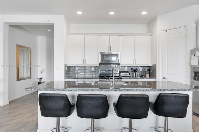 1403 SW 113th Ave, Pembroke Pines, FL 33025 - kitchen featuring stainless steel microwave, tasteful backsplash, a breakfast bar, white cabinets, and recessed lighting