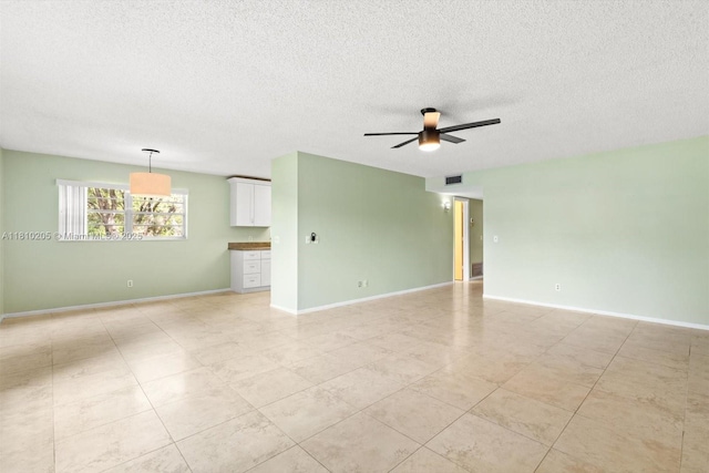 20 Lake Vista Trl Unit 107, Port St Lucie, FL 34952 - spare room featuring ceiling fan, a textured ceiling, baseboards, and light tile patterned floors