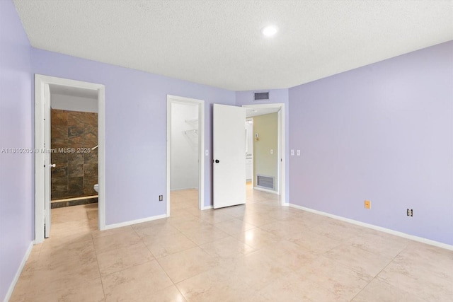 20 Lake Vista Trl Unit 107, Port St Lucie, FL 34952 - unfurnished bedroom featuring a textured ceiling, a walk in closet, baseboards, light tile patterned flooring, and a closet