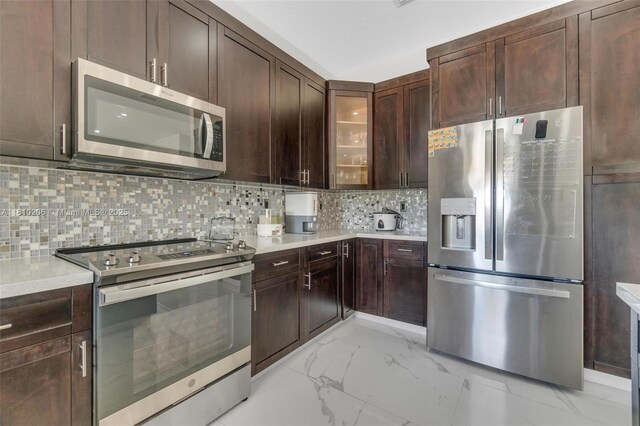 21305 SW 177th Ct, Miami, FL 33187 - kitchen featuring appliances with stainless steel finishes, light marble finish floors, light countertops, dark brown cabinets, and backsplash