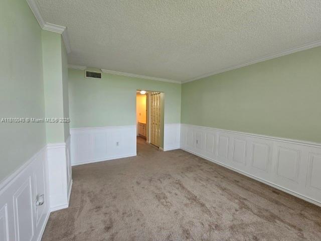 900 Colony Point Cir Unit 505, Pembroke Pines, FL 33026 - spare room featuring crown molding, a wainscoted wall, a textured ceiling, and carpet flooring